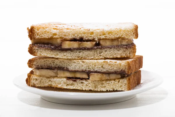 Sladký sendvič s čokoládová pasta a banán na bílé plotně — Stock fotografie