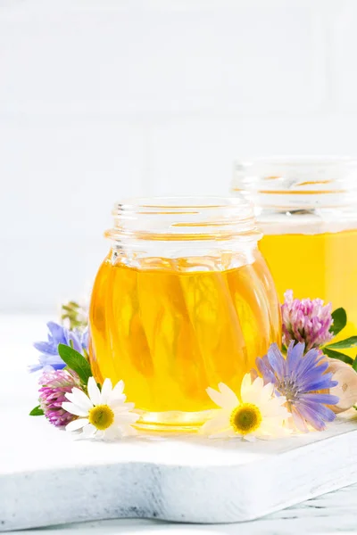 jars with fresh flower honey on white background, vertical