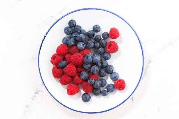 Plate with berries on a white background, top view — Stock Photo, Image