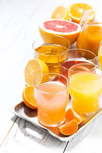 Assortment of fresh citrus juices on white table, vertical — Stock Photo, Image
