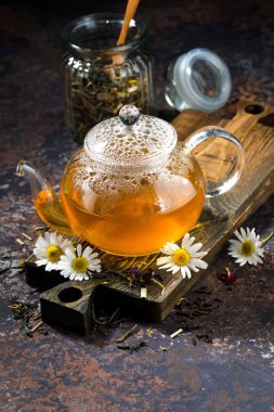 Papatya çayı bir cam çaydanlık ve koyu arka plan, dikey