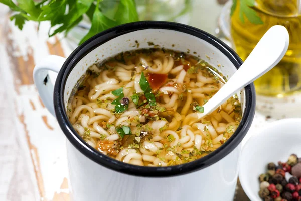 hot soup with noodles in a mug, closeup