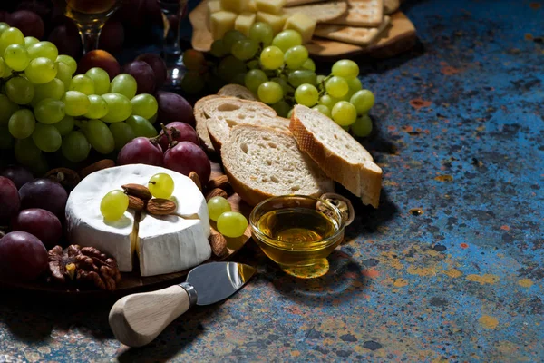 Snacks, fruta y queso Camembert sobre un fondo oscuro — Foto de Stock