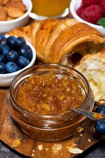 Croissant, pomerančová marmeláda a čerstvé jahody na dřevěném prkénku — Stock fotografie