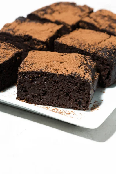 El postre - los pedazos de los brownies de chocolate sobre la mesa blanca, vertical —  Fotos de Stock