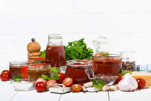 Sughi di pomodoro, pasta e ingredienti freschi sul tavolo di legno bianco — Foto Stock