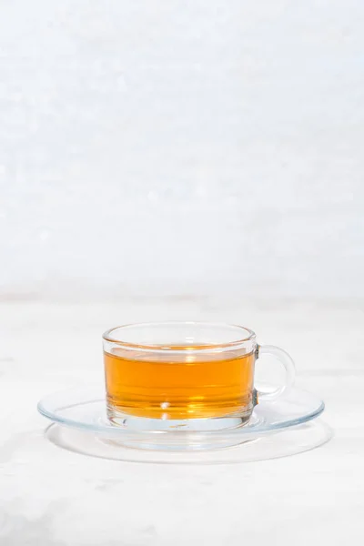 Illatos tea, egy üveg csésze fehér háttérrel, függőleges — Stock Fotó