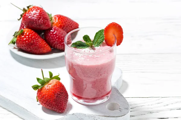 Refreshing strawberry milkshake on white table — Stock Photo, Image