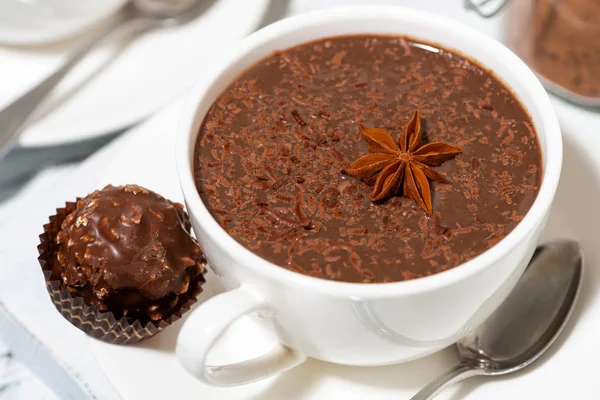 Tazza di cioccolata calda e caramelle al cioccolato sul tavolo bianco, primo piano — Foto Stock