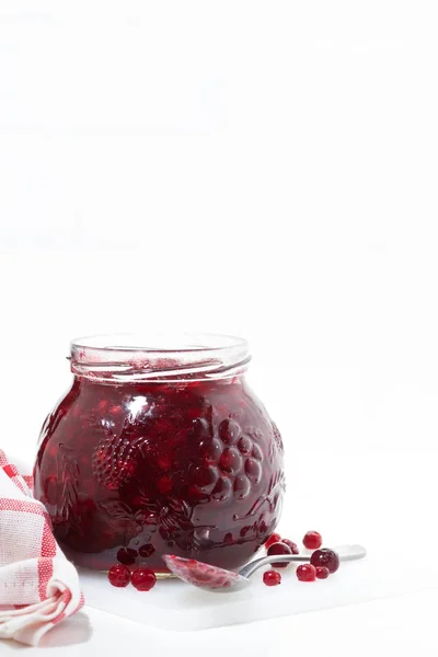 Glass jar of cranberry jam on a white table, vertical — Stock Photo, Image