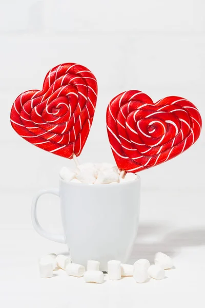 Candy on a stick in the form of hearts in a white cup, vertical — Stock Photo, Image