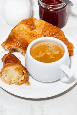 Bir fincan espresso ve beyaz arka planda taze kruvasan.