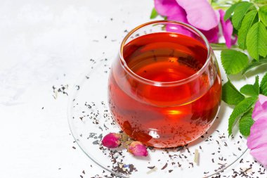 beyaz bir masa üzerinde bir cam fincan yabani gül ile kokulu çay
