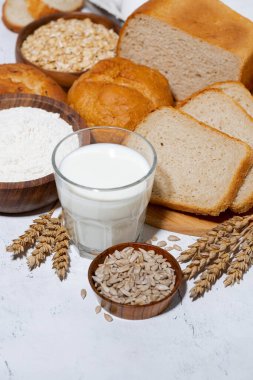 Çeşitli taze ekmek çeşitleri, beyaz arka planda bir bardak süt, üst manzara.