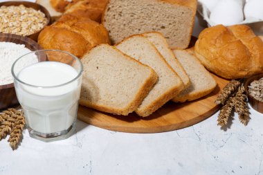 Çeşitli taze ekmek çeşitleri, beyaz arka planda bir bardak süt, üst taraf yakın çekim