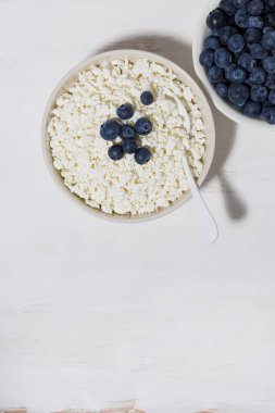 Taze tarım ürünleri, süzme peynir ve beyaz arka planda yabanmersini.