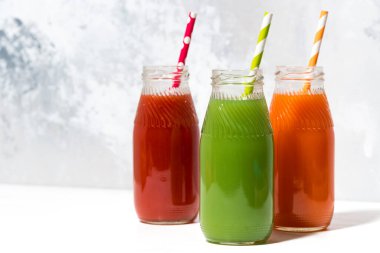 Beyaz arka planda şişelerde çeşitli taze meyve suları, yakın plan