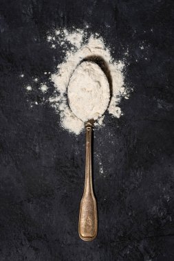 Siyah arkaplanda buğday unlu kaşık, yakın çekim üst görünümü