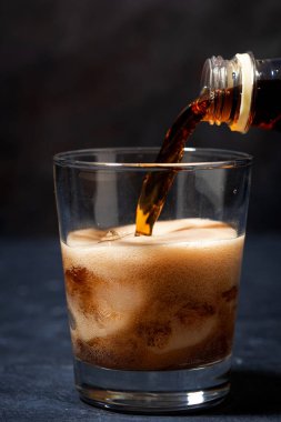 Coca Cola şişeden bardağa dökülüyor, yakın plan.
