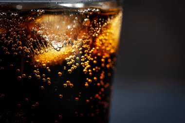 Siyah arka planda buzlu bir bardak Coca Cola, yakın plan.