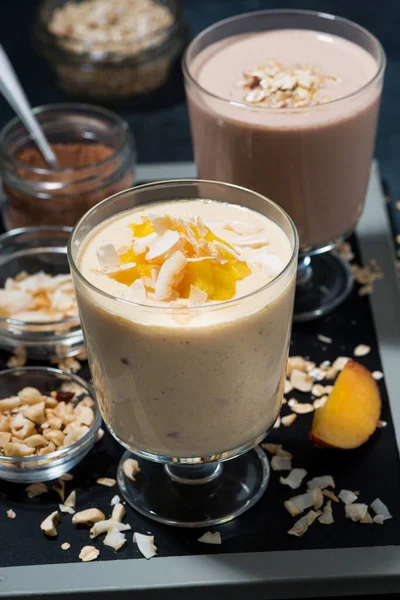 milkshakes with chocolate, oatmeal and mango in glasses, top view