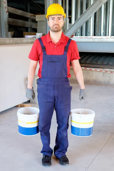 Pracovník podniku kbelíky na staveništi — Stock fotografie