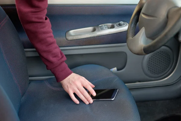 Χέρι του ένας κλέφτης κλέβει ένα κινητό τηλέφωνο από ένα παρκαρισμένο αυτοκίνητο — Φωτογραφία Αρχείου