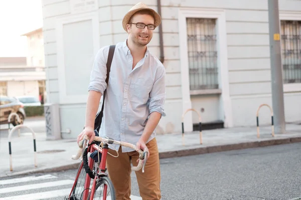 Fashionable man holding his bike in the city street