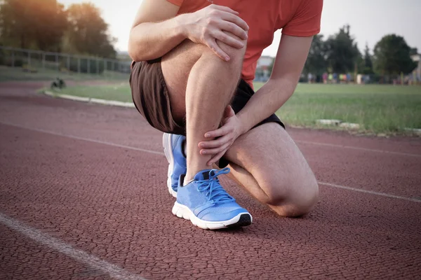 Corredor con el tobillo lesionado en la pista —  Fotos de Stock