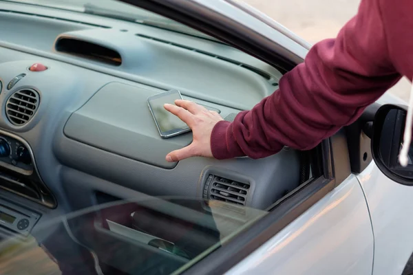 주차 된 차에서 휴대 전화를 훔친 도둑의 손 — 스톡 사진