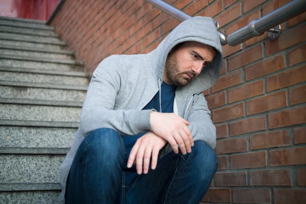 Lonely Man Leaning on an urban wall seated on the stairs