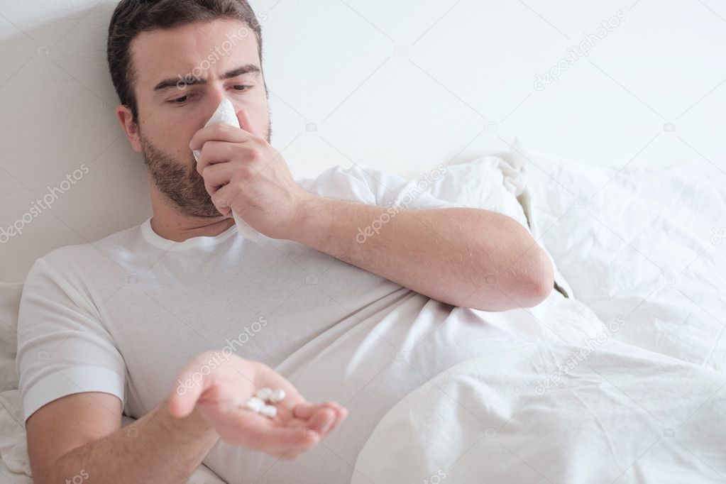 Man taking medicine pills lying in the bed