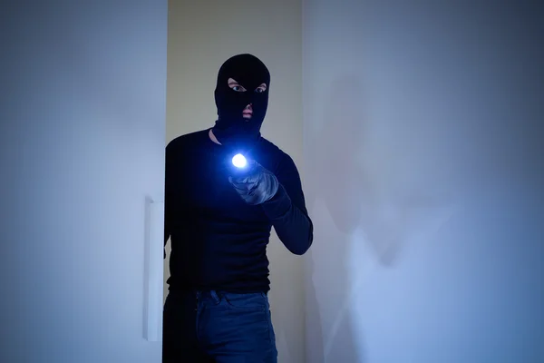 Burglar wearing a balaclava holding a flashlight — Stock Photo, Image