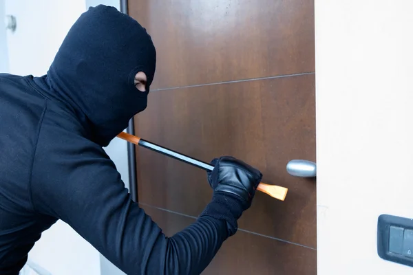 Ladrón tratando de forzar una cerradura de puerta usando una palanca — Foto de Stock