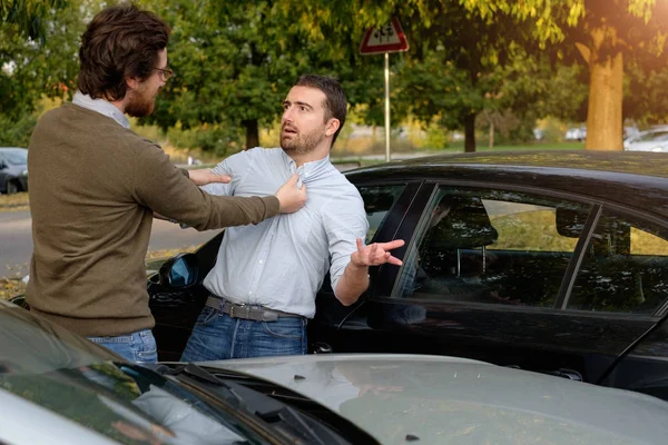 Двое мужчин спорят после автомобильной аварии на дороге — стоковое фото