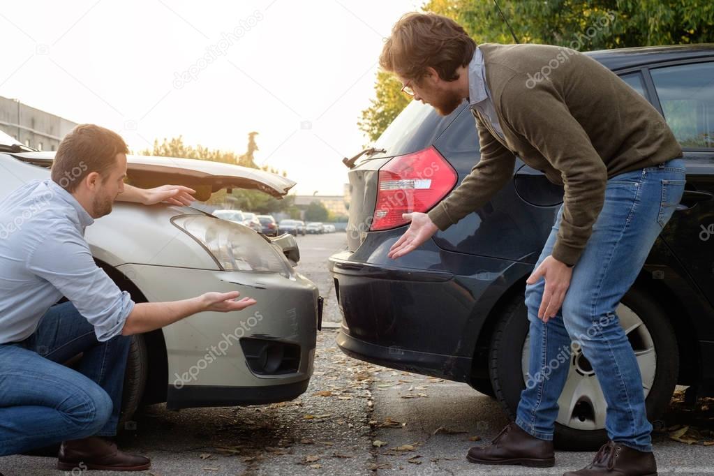 Two men arguing after a car accident on the road