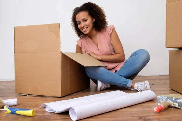 Happy woman surrounded by large boxes ready for home relocation