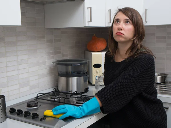 Mujer aburrida limpiando la superficie de gas de acero inoxidable en la cocina —  Fotos de Stock