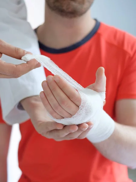 Médico bandaging a mão de um homem do esporte após um acidente — Fotografia de Stock