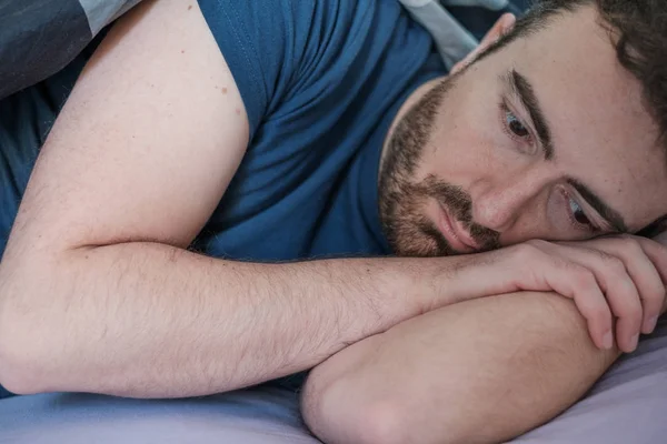 Deprimerad man ligger i sin säng må dåligt — Stockfoto