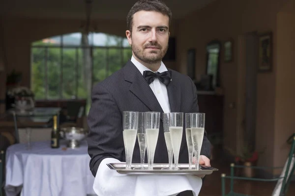 Profesyonel garson formasıyla şampanya hizmet vermektedir — Stok fotoğraf