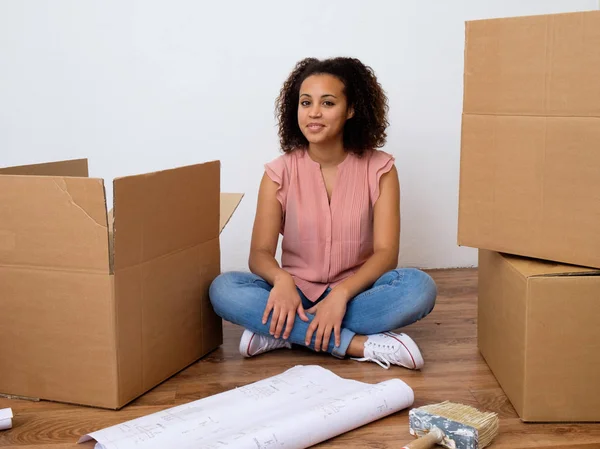 Happy woman surrounded by large boxes ready for home relocation