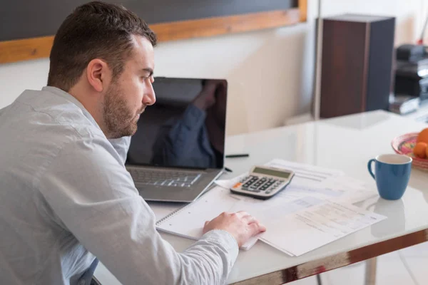 Frustrated man calculating bills and tax outcomes — Stock Photo, Image