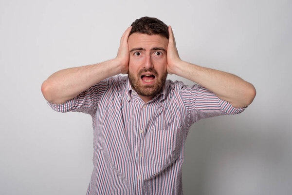 Мужчина с руками на ушах раздражен

