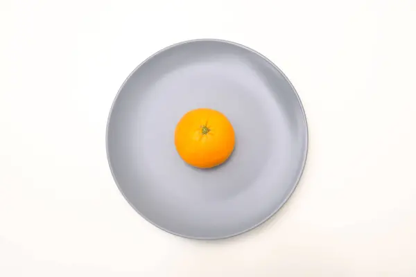 Naranja en un plato sobre fondo blanco — Foto de Stock