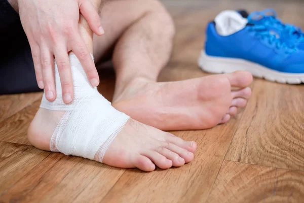 Esportista massageando seu tornozelo ferido — Fotografia de Stock
