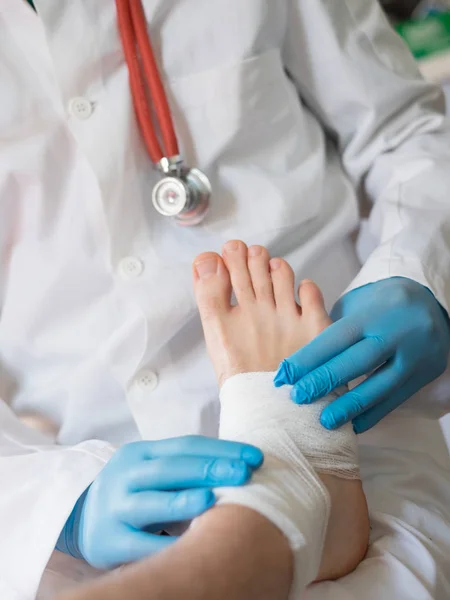 Primer plano del médico vendando un pie lesionado —  Fotos de Stock