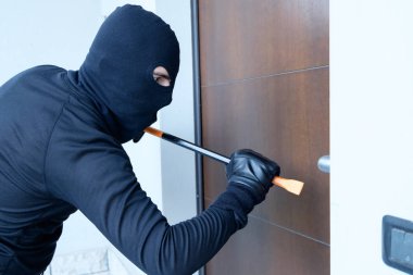Hırsız levye kullanarak bir kapı kilidi zorlamak için çalışıyor