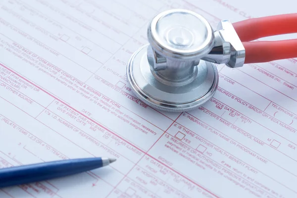 Formulario de reclamo de seguro de salud con pluma y estetoscopio — Foto de Stock