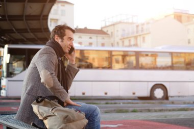 Otobüs durağında bekleyen ve cep telefonda konuşurken adam